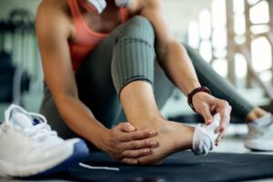 Close up of athletic woman injured her foot during workout at the gym