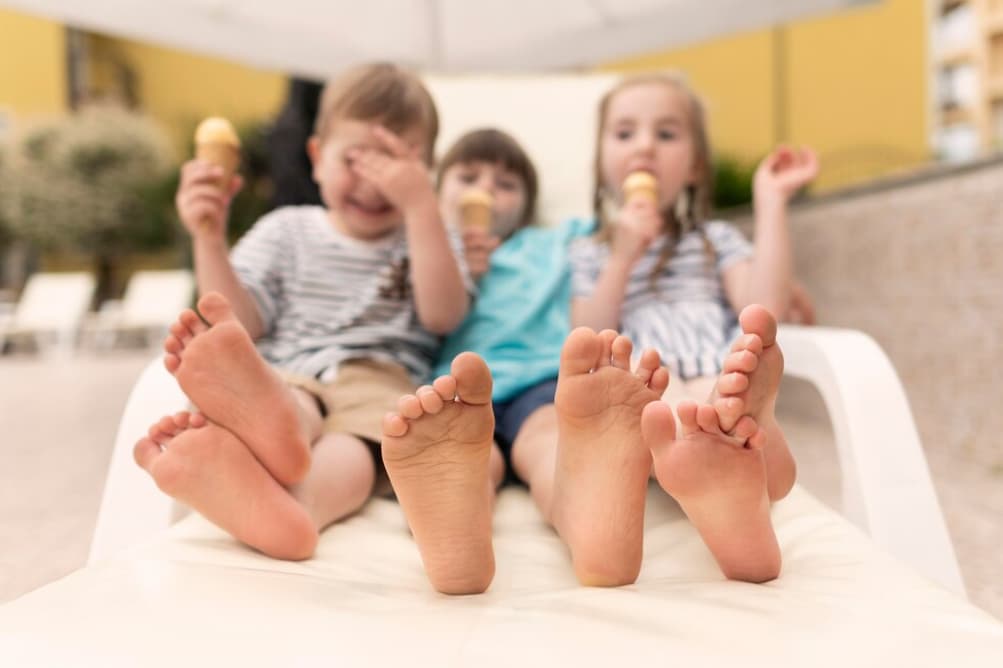 Three children with bare feet showing as they eat ice cream