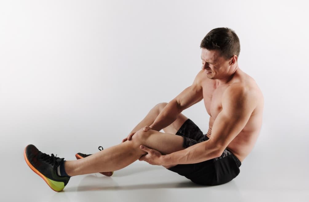 An athlete on the floor clutching his leg in pain, possibly injured