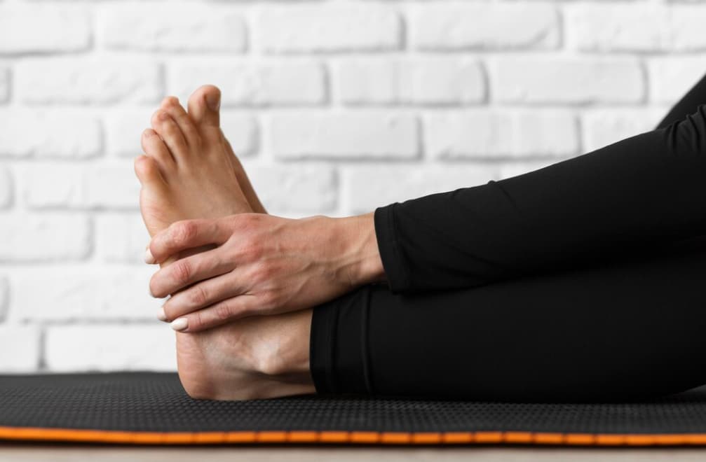 person stretching their feet, touching their toes, likely doing yoga or stretching