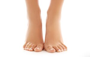 Two bare feet standing with visibly curled toes against a white background
